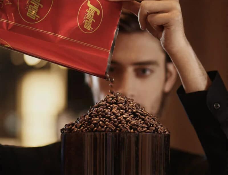 pouring extra strong coffee beans into grinder hopper